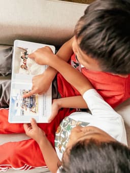 Kids reading their personalized Storybook Firsts board book together on the couch
